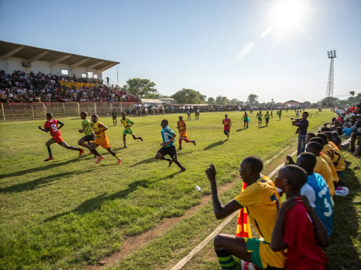 A dynamic image capturing a local football tournament, with players competing and spectators cheering. The scene highlights the excitement and community spirit of the event, showcasing local talent and healthy competition.